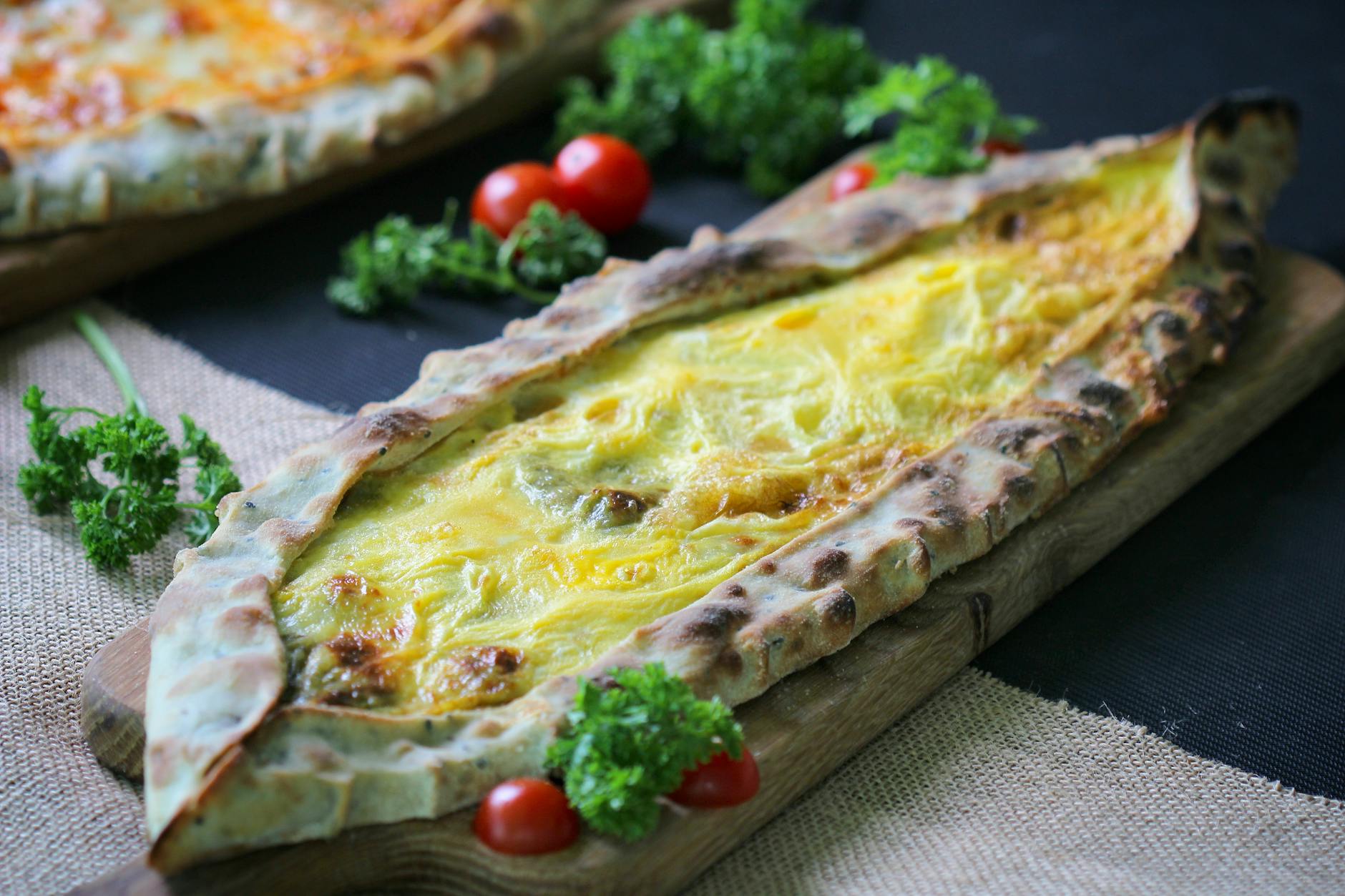 Traditional boat-shaped Turkish pide filled with melted cheese and a soft egg.