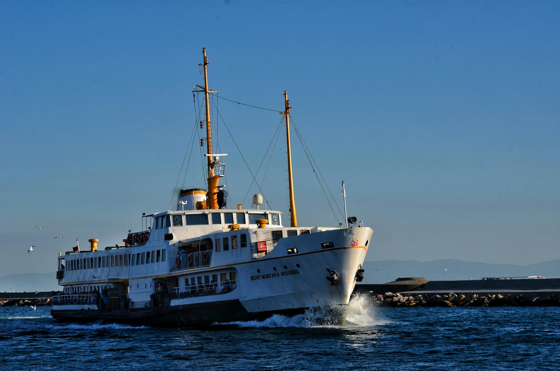 A traditional white and yellow passenger ferry sailing across the Bosphorus in Istanbul.