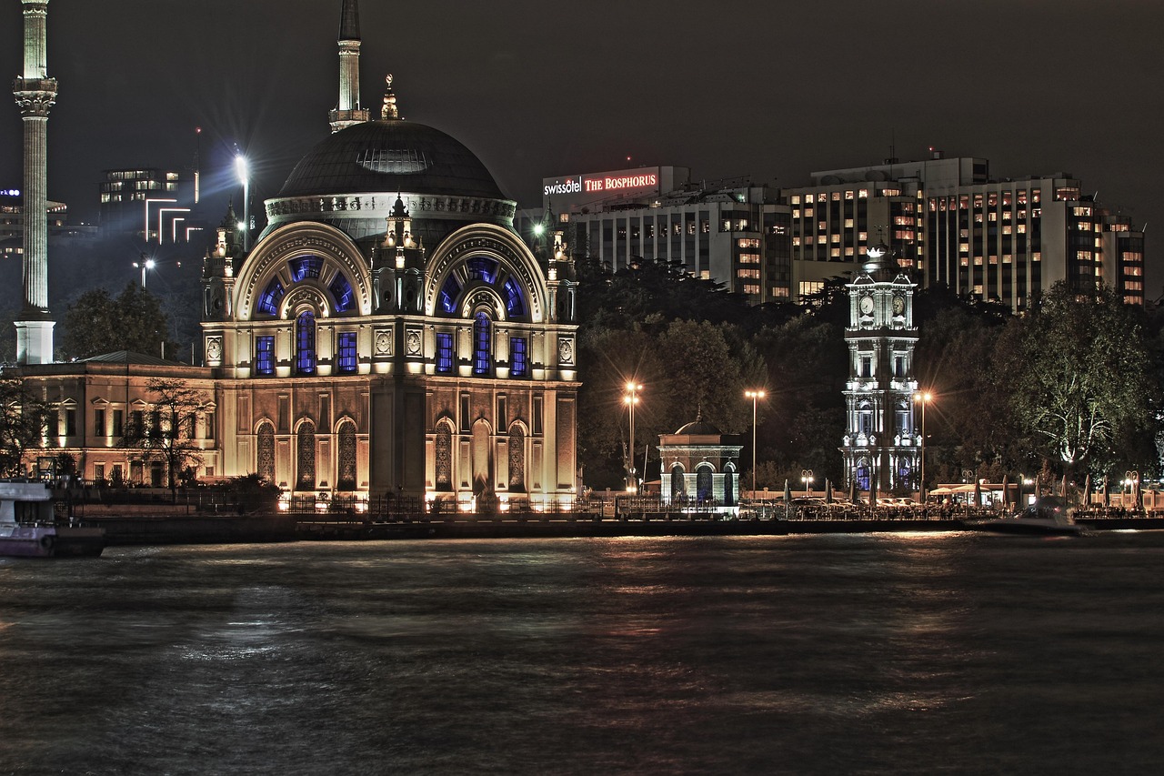 Beautiful night view of the Dolmabahçe Mosque and Clock Tower along the Bosphorus waterfront.