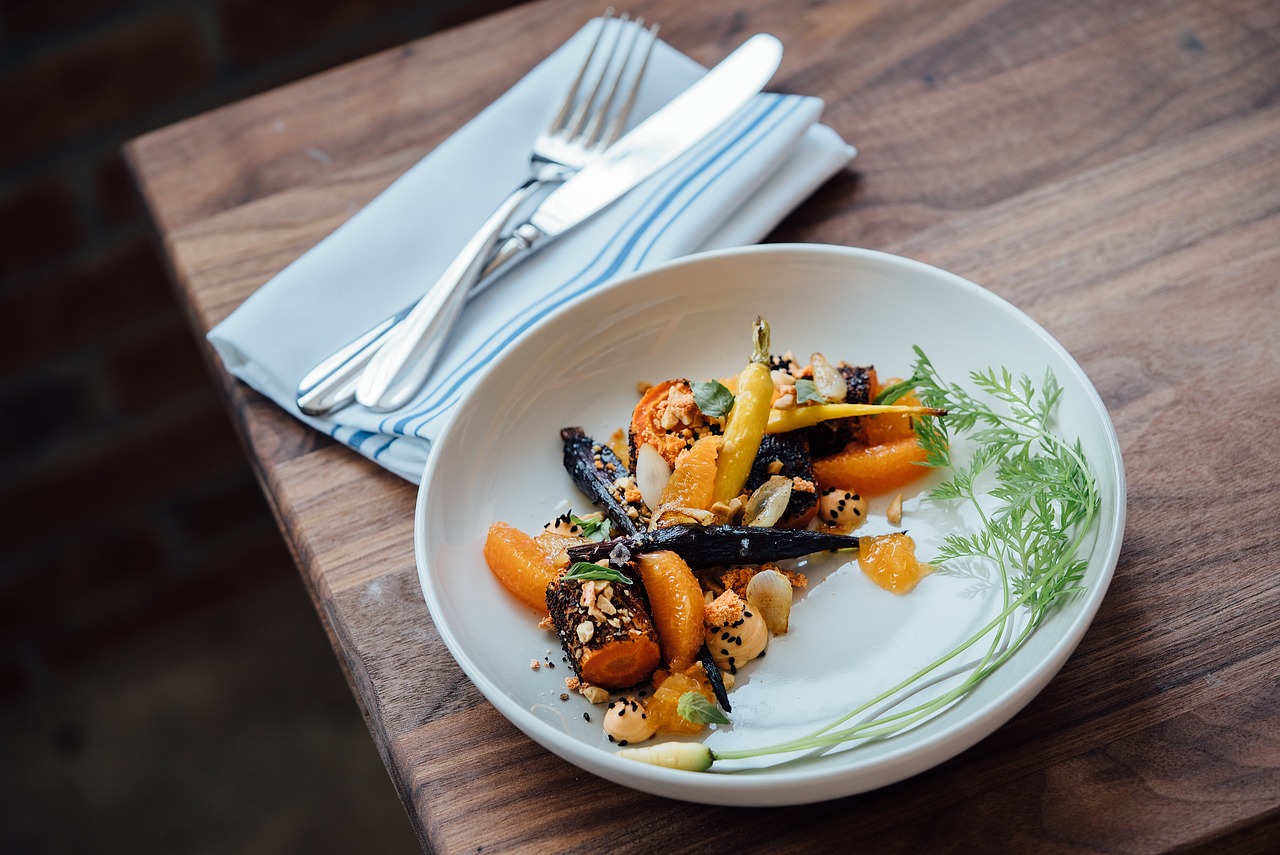 Roasted carrots and citrus segments artfully arranged on a white plate.