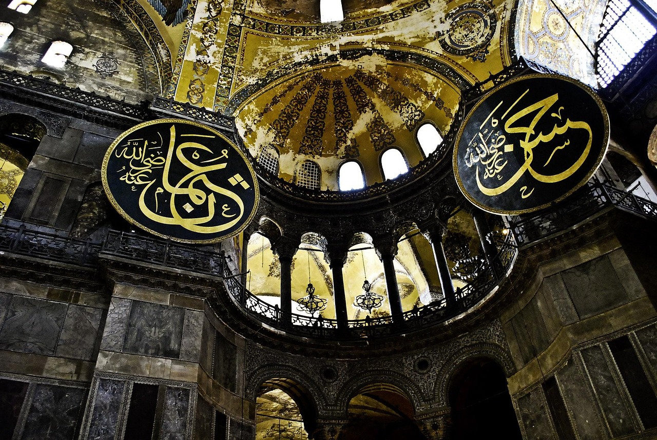 Interior view of Hagia Sophia showing its grand dome and large calligraphy medallions.