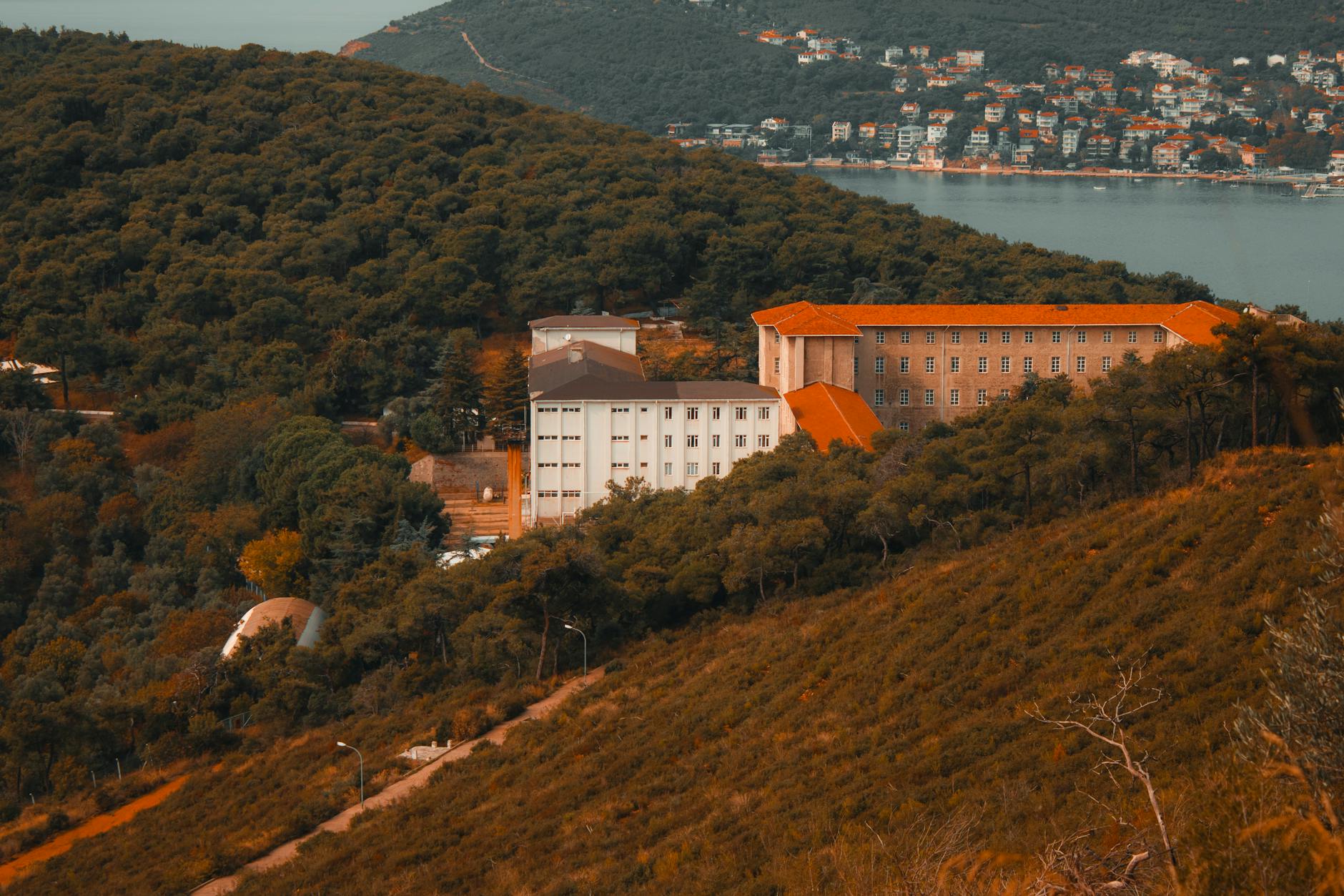 The historic Halki Seminary building surrounded by dense green forest paths on Heybeliada.