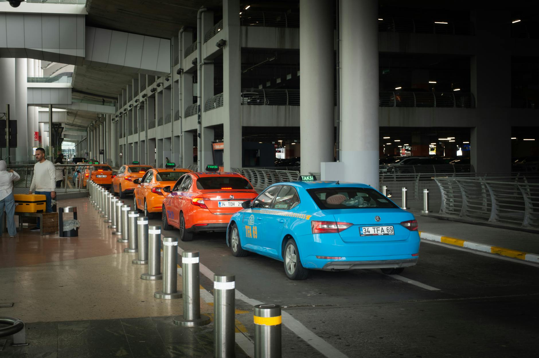A row of yellow, orange, and blue taxis waits for passengers at Istanbul Airport.