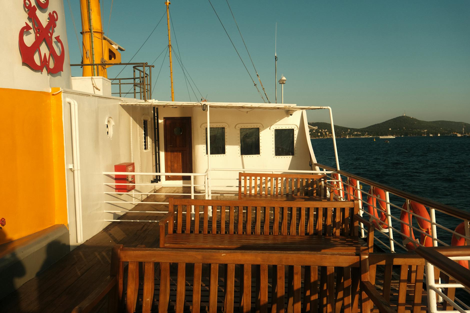 Wooden benches on the passenger deck of a traditional ferry heading to islands.