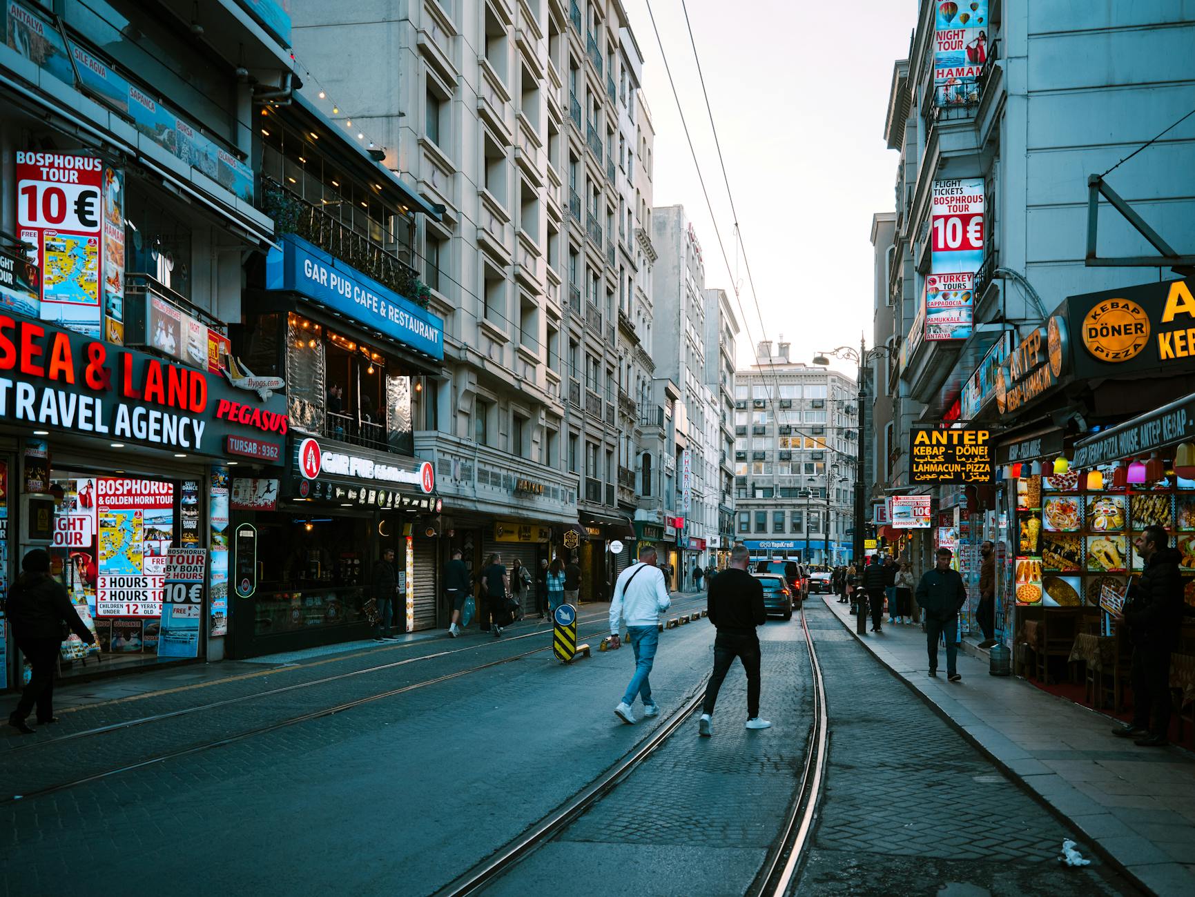 A busy urban street in Turkey lined with various kebab and döner restaurants during the day.