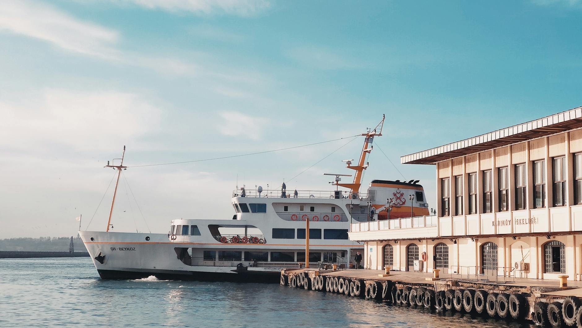 A white passenger ferry departs from the historic Kadıköy pier in Istanbul.