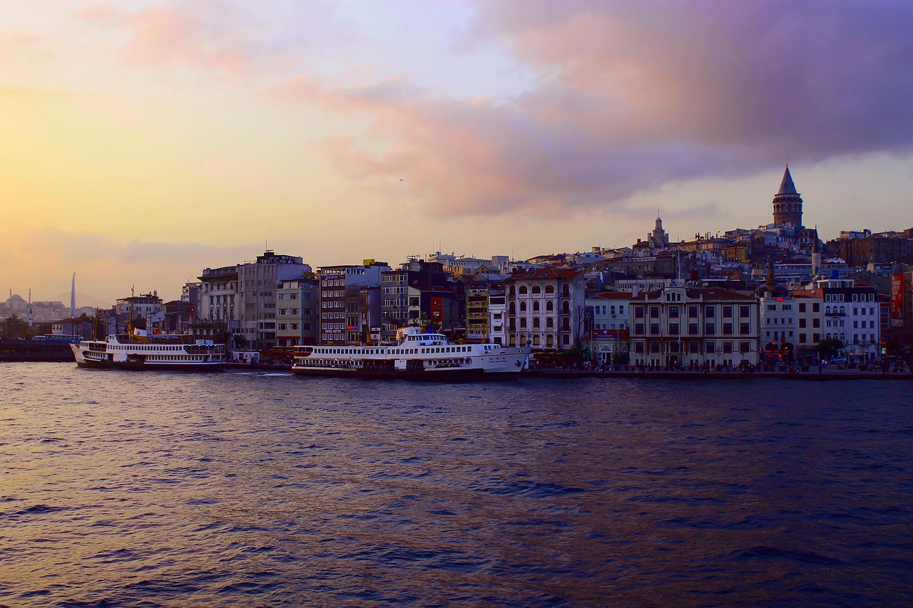 The Karaköy waterfront in Istanbul features the iconic Galata Tower and passenger ferries at sunset.