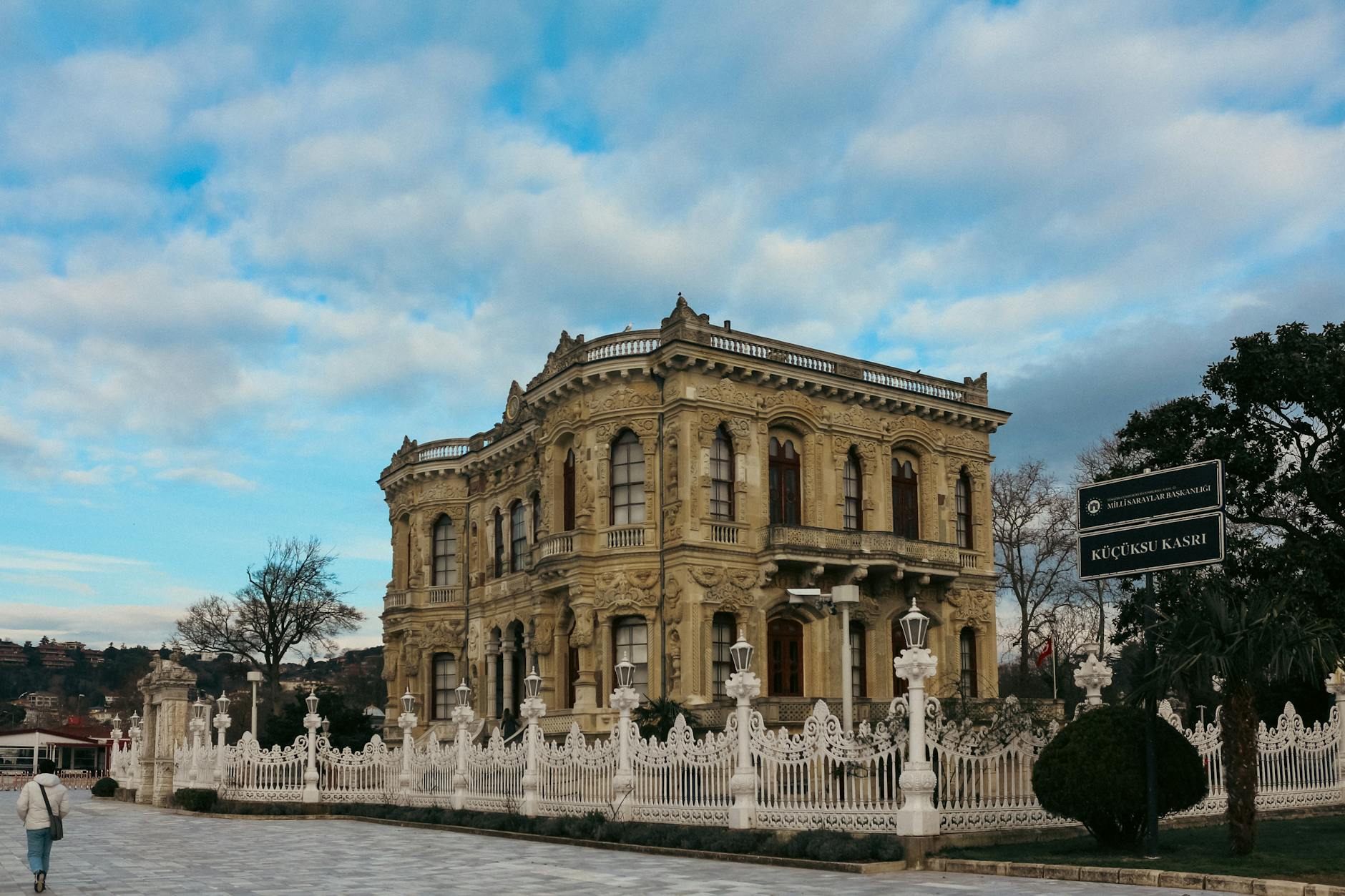 The ornate facade of Kucuksu Pavilion in Istanbul under a cloudy blue sky.