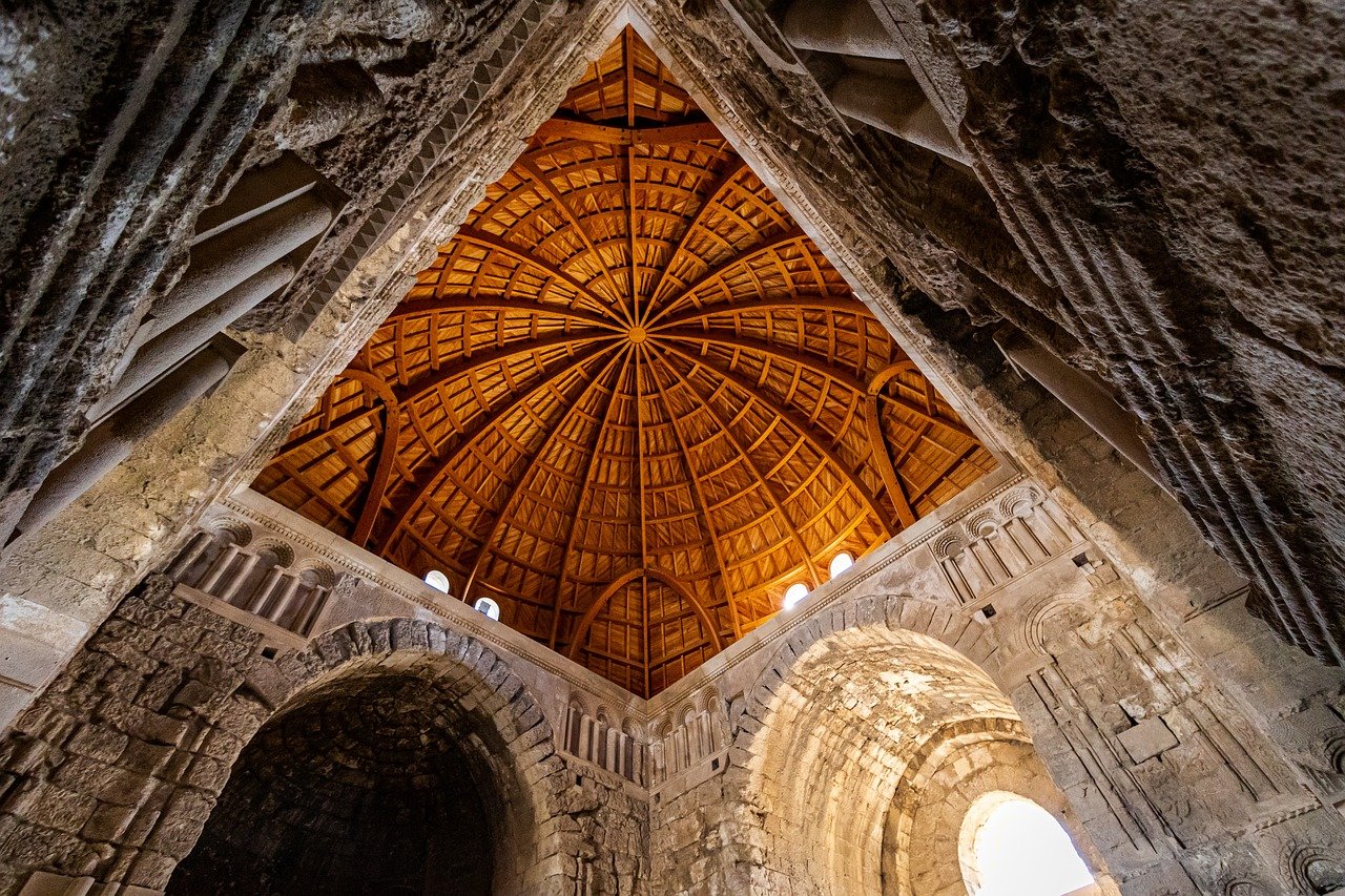 A dramatic low-angle interior view showcasing the intricate, radiating wooden latticework of the dome ceiling inside the Little Hagia Sophia (Küçük Ayasofya Camii) in Istanbul, contrasting with the rough, historic stone arches and walls below. This unique architectural detail makes it an excellent alternative when one is done with the Sultanahmet crowds so I go to Little Hagia Sophia instead.