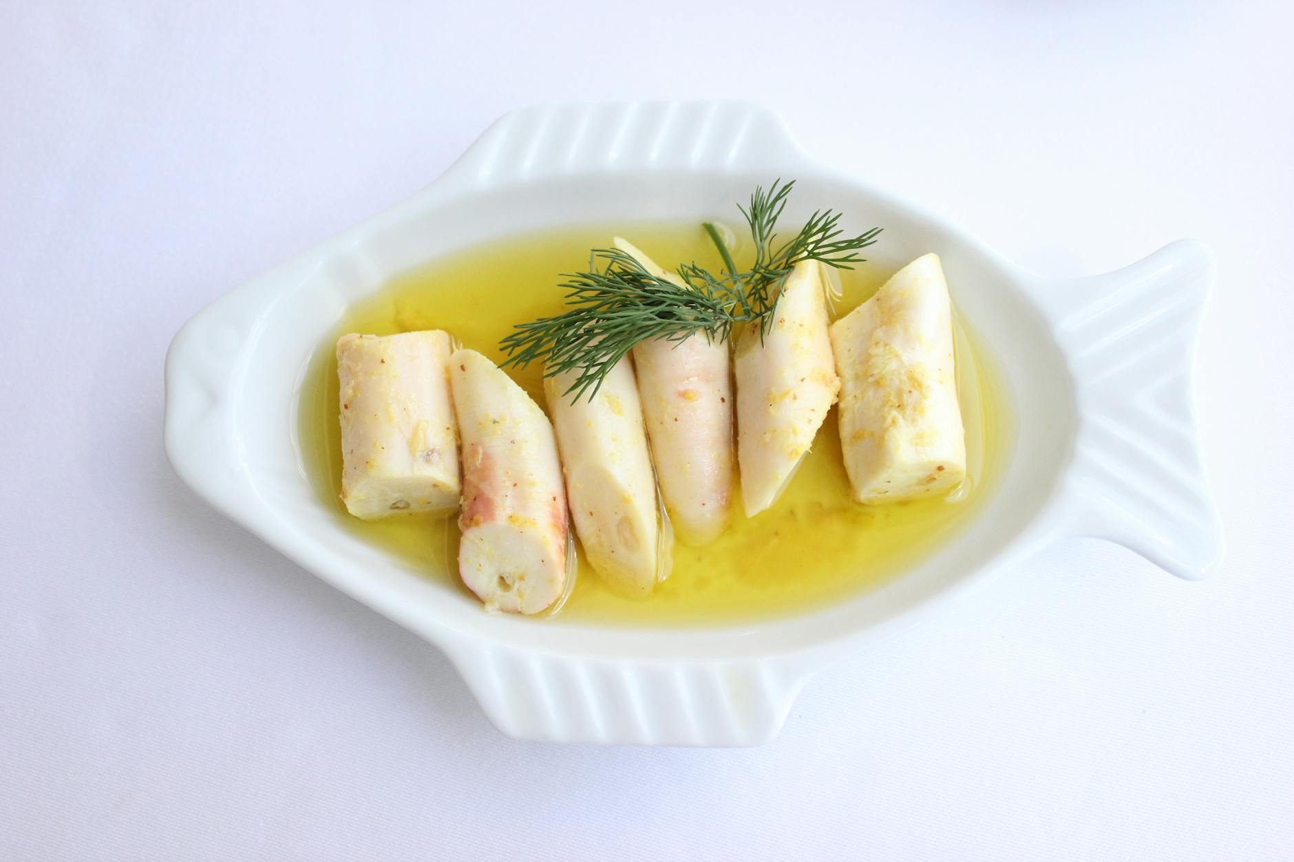 Sliced artichoke hearts marinated in golden olive oil and garnished with fresh dill.