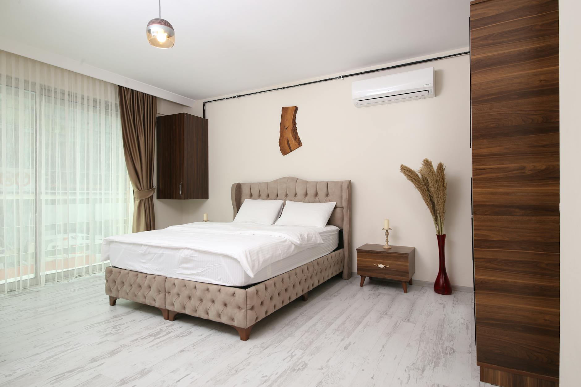Modern, clean bedroom interior featuring a tufted bed, light wood-look flooring, and natural decor, suitable for an Istanbul short-term rental.