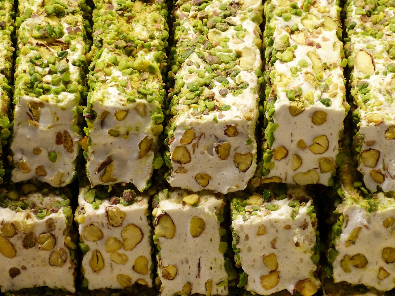 Close-up of premium white Turkish delight generously filled and coated with vibrant green pistachios.
