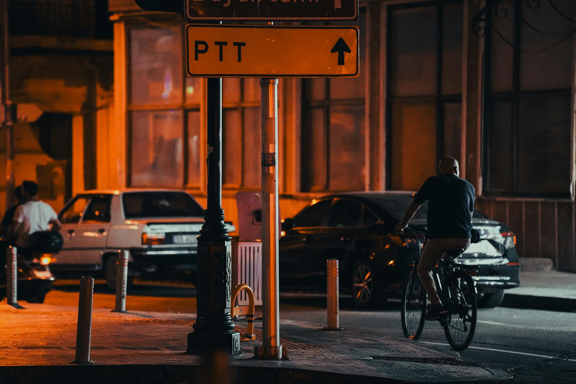 A yellow street sign with an arrow points toward a Turkish PTT post office branch.