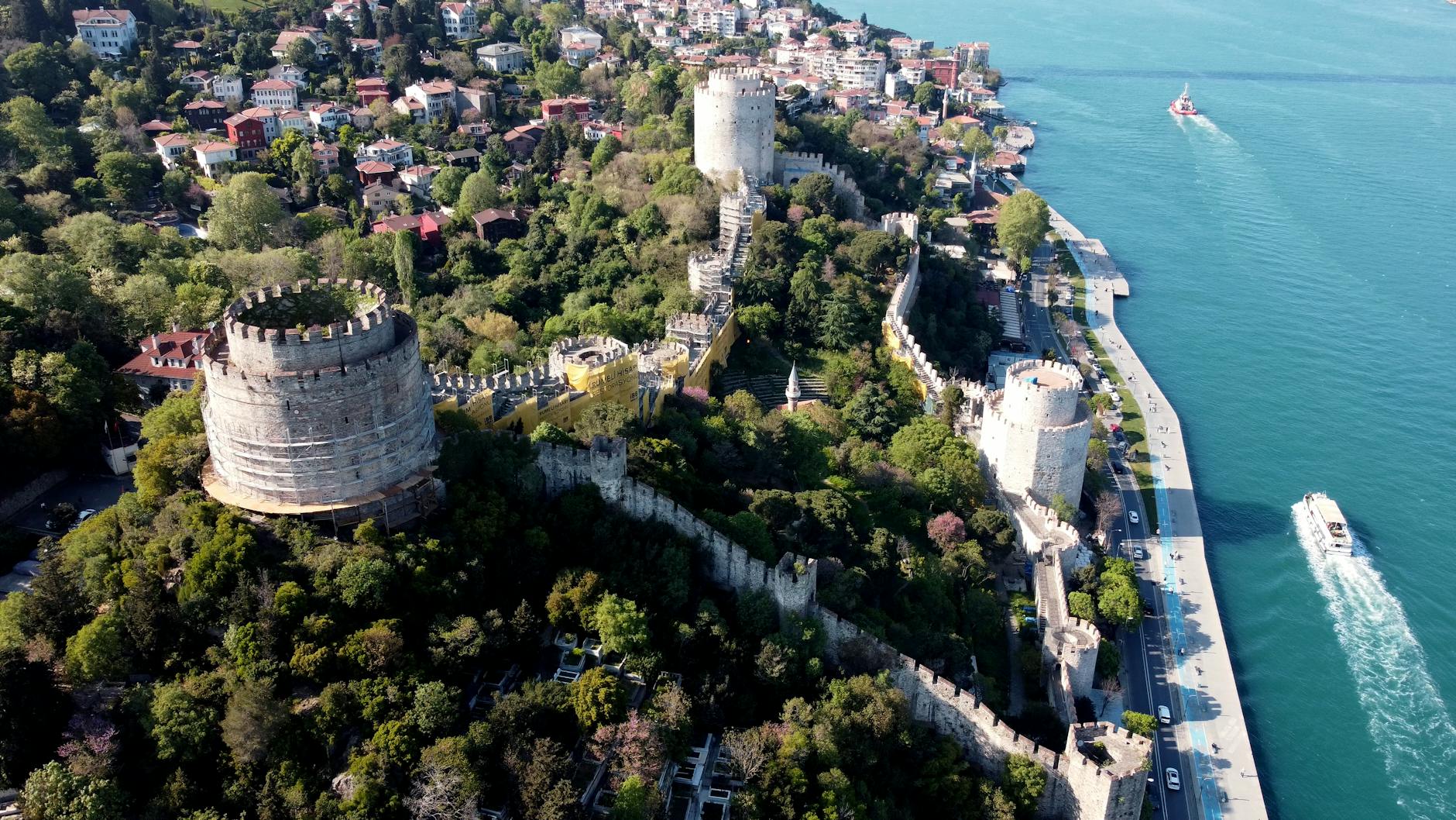 Aerial view of Rumeli Hisarı fortress walls and towers overlooking the turquoise Bosphorus strait in Istanbul.