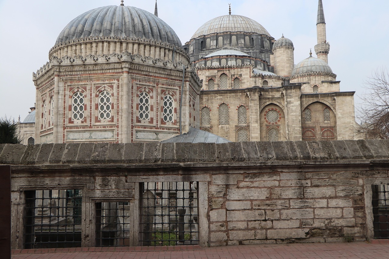 Exterior stone walls and ornate domes of the Sehzade Mosque complex in Istanbul.