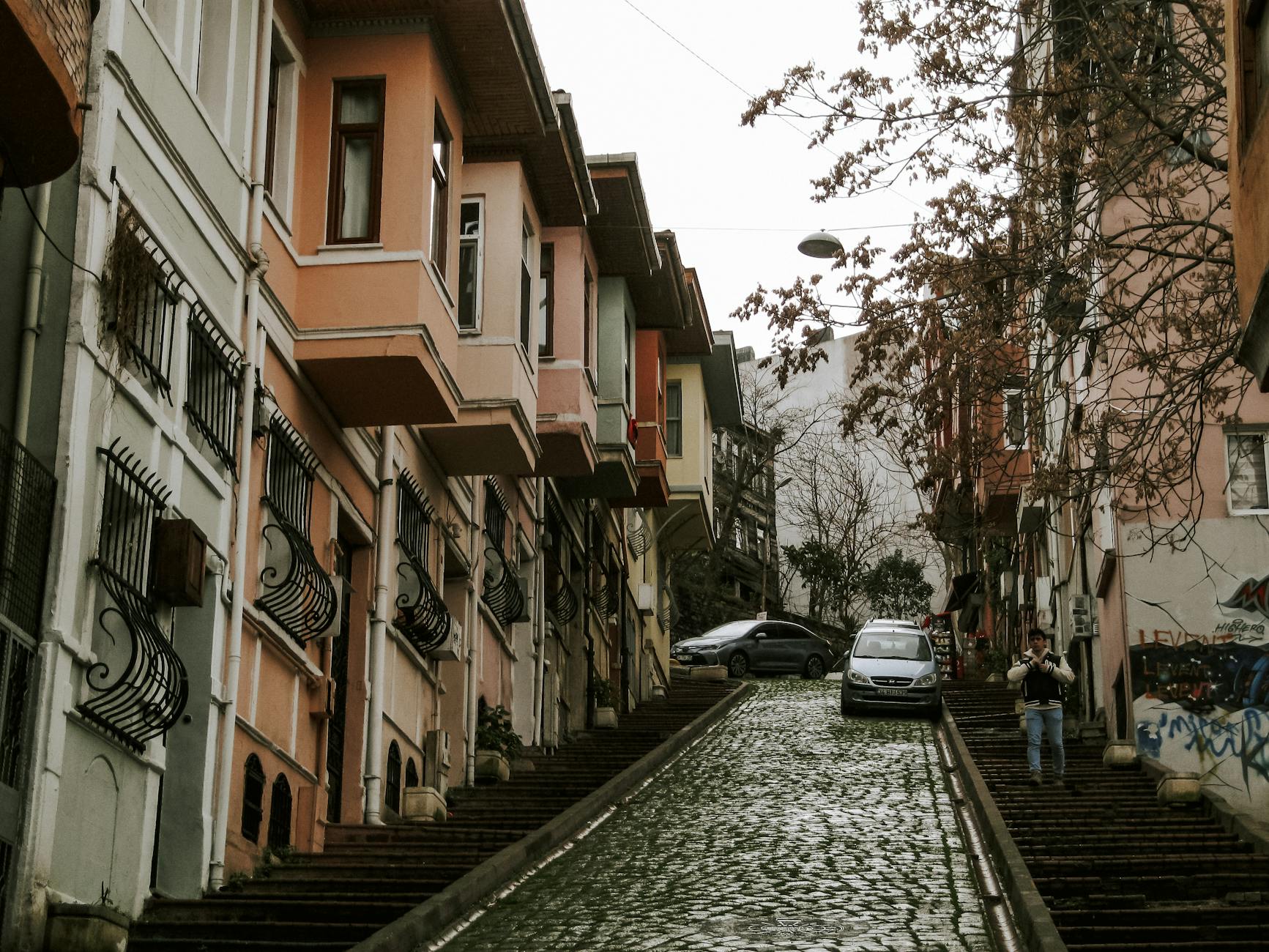A steep cobblestone street with stone staircases on either side between colorful buildings.