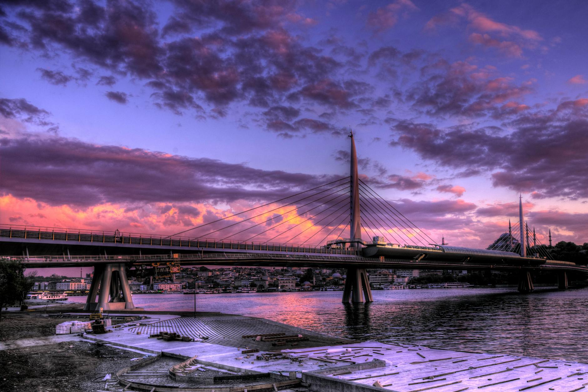 Vibrant purple and orange sunset clouds fill the sky above the Golden Horn bridge.