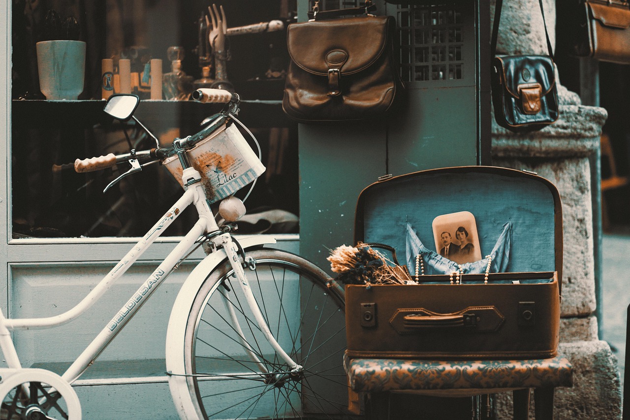 A vintage white bicycle and antique suitcase are displayed outside a creative shop in Yeldeğirmeni.