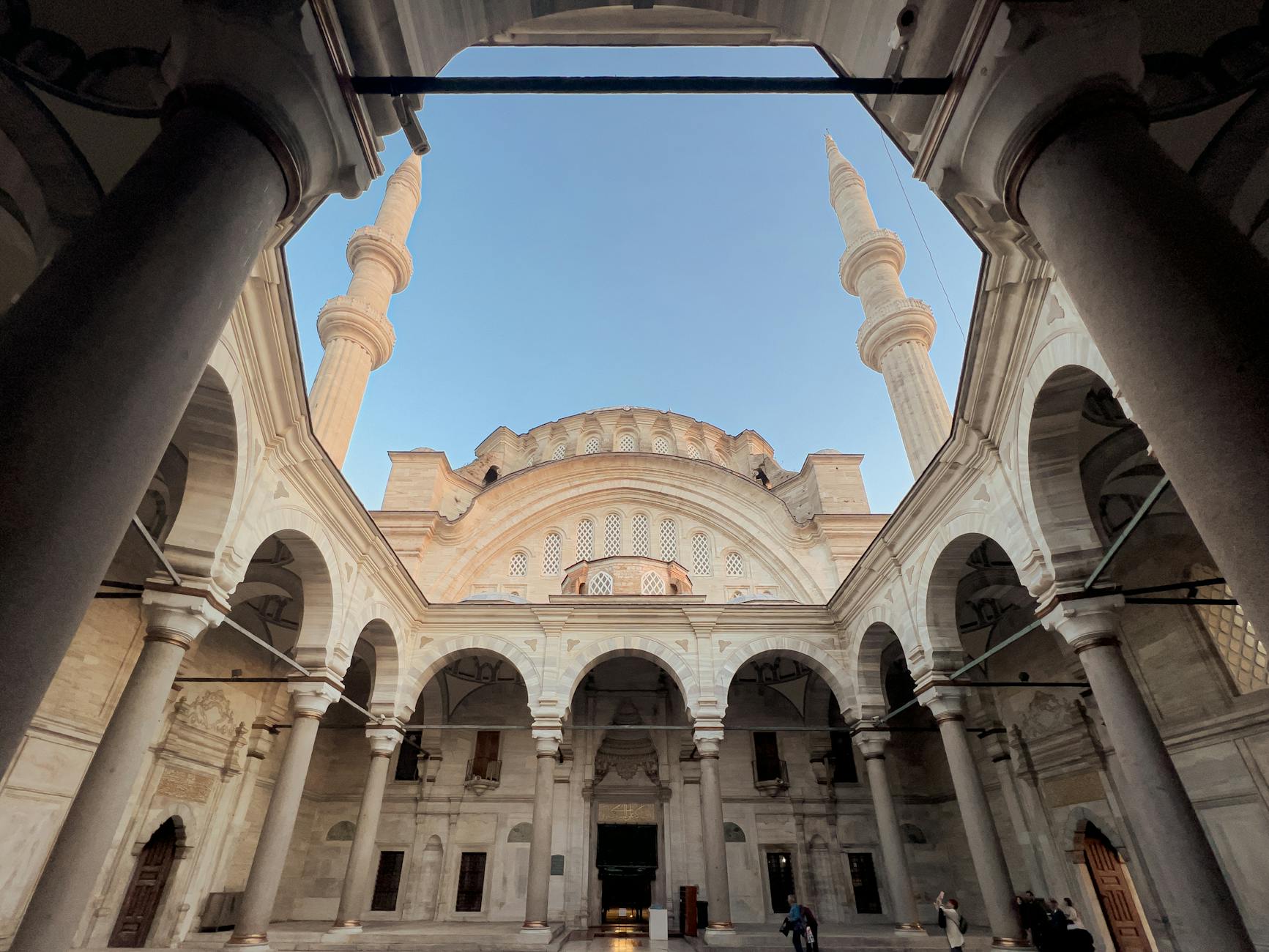 A wide view of the quiet inner courtyard at Yavuz Selim Mosque under a clear blue sky.